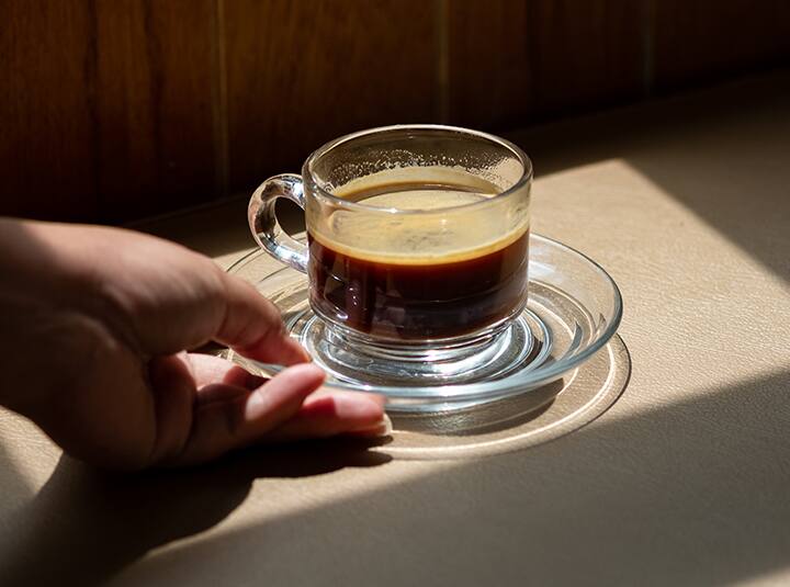 Ręka podająca kawę z przezroczystej filiżance 