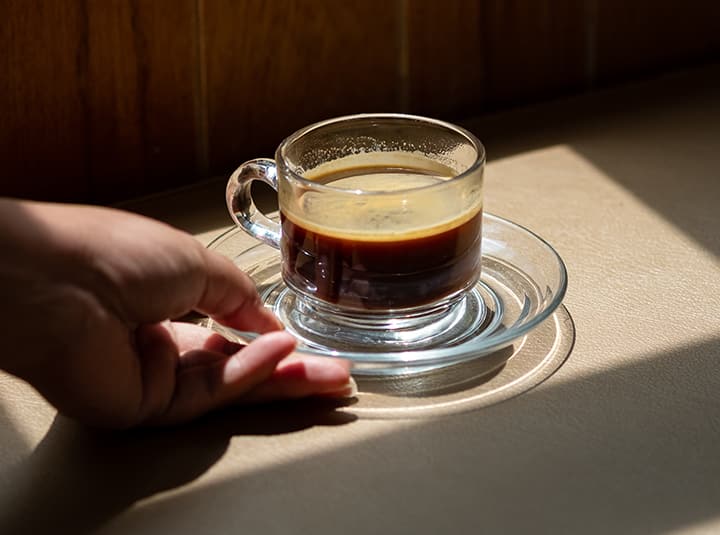 Ręka podająca kawę w przezroczystej filiżance 