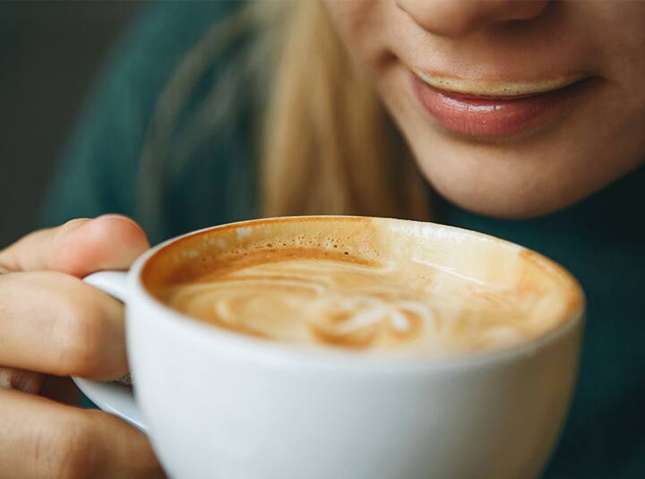 Zbliżenie na kobietę pijącą kawę z mleczną pianką z filiżanki