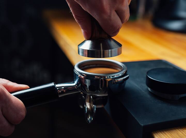 Dłoń tampingująca kawę w tamperze